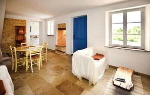 A room with a dining table, chairs, a covered sofa, a wooden coffee table, a blue door, and a window with a view. - 2 bedroom amazing home in Saint-Trinit (Saint-Trinit)