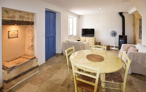A living room with a round table, chairs, a television, a fan, and a fireplace. - 2 bedroom amazing home in Saint-Trinit (Saint-Trinit)