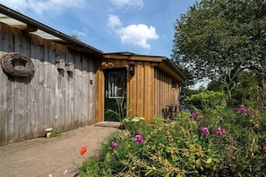 A wooden building with a door, a window, and a small porch area. - Holiday apartment "Karla" (Ahrenviölfeld, Deutschland)