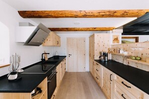 Eine Küche mit Holzausstattung, einer schwarzen Arbeitsplatte und einem Holzbalken an der Decke.