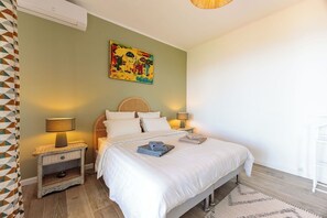 Ein Schlafzimmer mit einem Bett, zwei Nachttischen mit Lampen, einem Wandbild und einem gemusterten Teppich.
