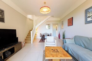 Ein Wohnzimmer mit Fernseher, einem Holztisch, einer Couch, einer Treppe und einem Essbereich.