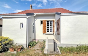 Ein weißes Gebäude mit rotem Ziegeldach, einem kleinen Fenster und Holzläden.