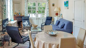 Un salon avec un canapé bleu, deux fauteuils, une table basse en verre et une cheminée.