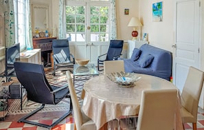 Ein Wohnzimmer mit einem blauen Sofa, zwei Sesseln, einem Glastisch und einem Kamin.
