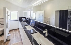 A modern bathroom with three sinks, a large mirror, and a black countertop. - Amazing home in Saint-Gervais (Saint-Gervais)