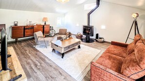 Ein Wohnzimmer mit einer Couch, einem Couchtisch, einem Fernseher, einem Kamin und einem Holzkasten.