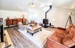 Ein Wohnzimmer mit einer Couch, einem Couchtisch, einem Fernseher, einem Kamin und einem Holzkasten.