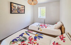 A bedroom with two beds, a window, a painting on the wall, and a hanging light fixture. - Amazing home in Saint-Gervais (Saint-Gervais)
