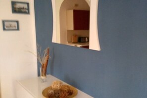 Ein Zimmer mit blauer Wand, einer weißen Arbeitsplatte und einem Spiegel, der eine Küche zeigt.