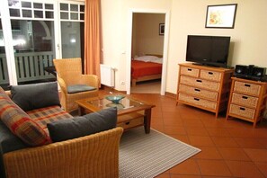 A furnished room with a sofa, a glass-top coffee table, a television, and a dresser. - No. 08 "Villa Laetitia" in Binz (Ostseebad Binz)