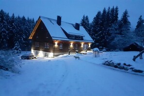 Ein Haus mit einem geneigten Dach, einem Schornstein und einem schneebedeckten Hof.