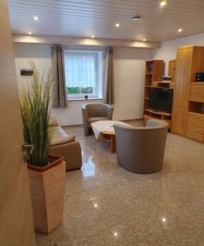 Ein modernes Wohnzimmer mit einer Couch, einem Sessel und einem Fernsehschrank.