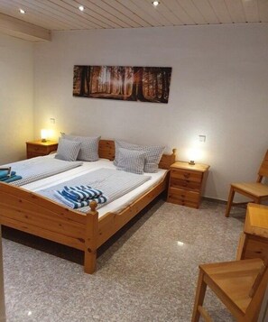Una camera da letto con un letto in legno, due comodini, una sedia, un quadro appeso alla parete e un pavimento tappezzato.