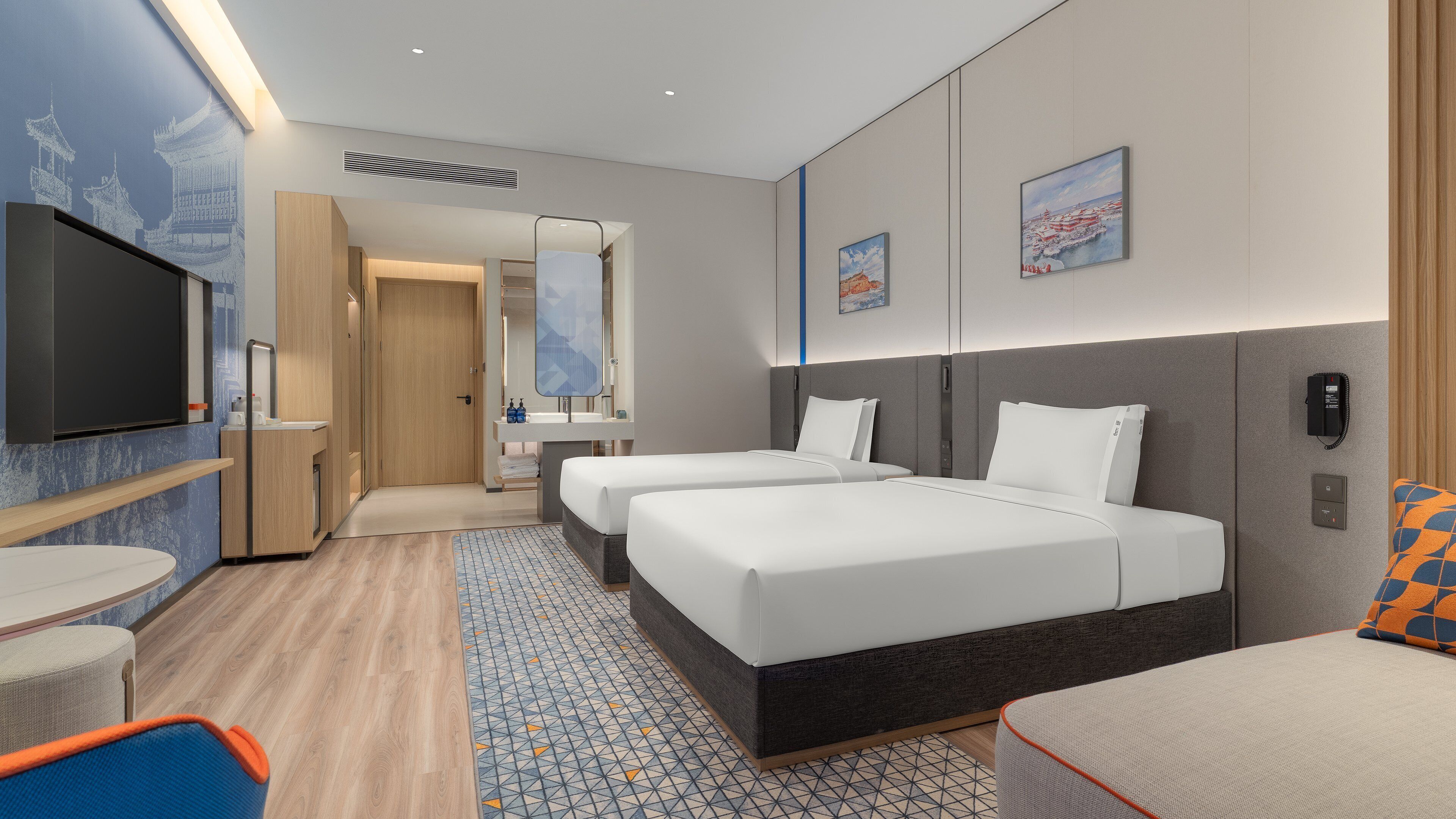 Habitación de hotel con dos camas, televisión, baño y obras de arte en las paredes.