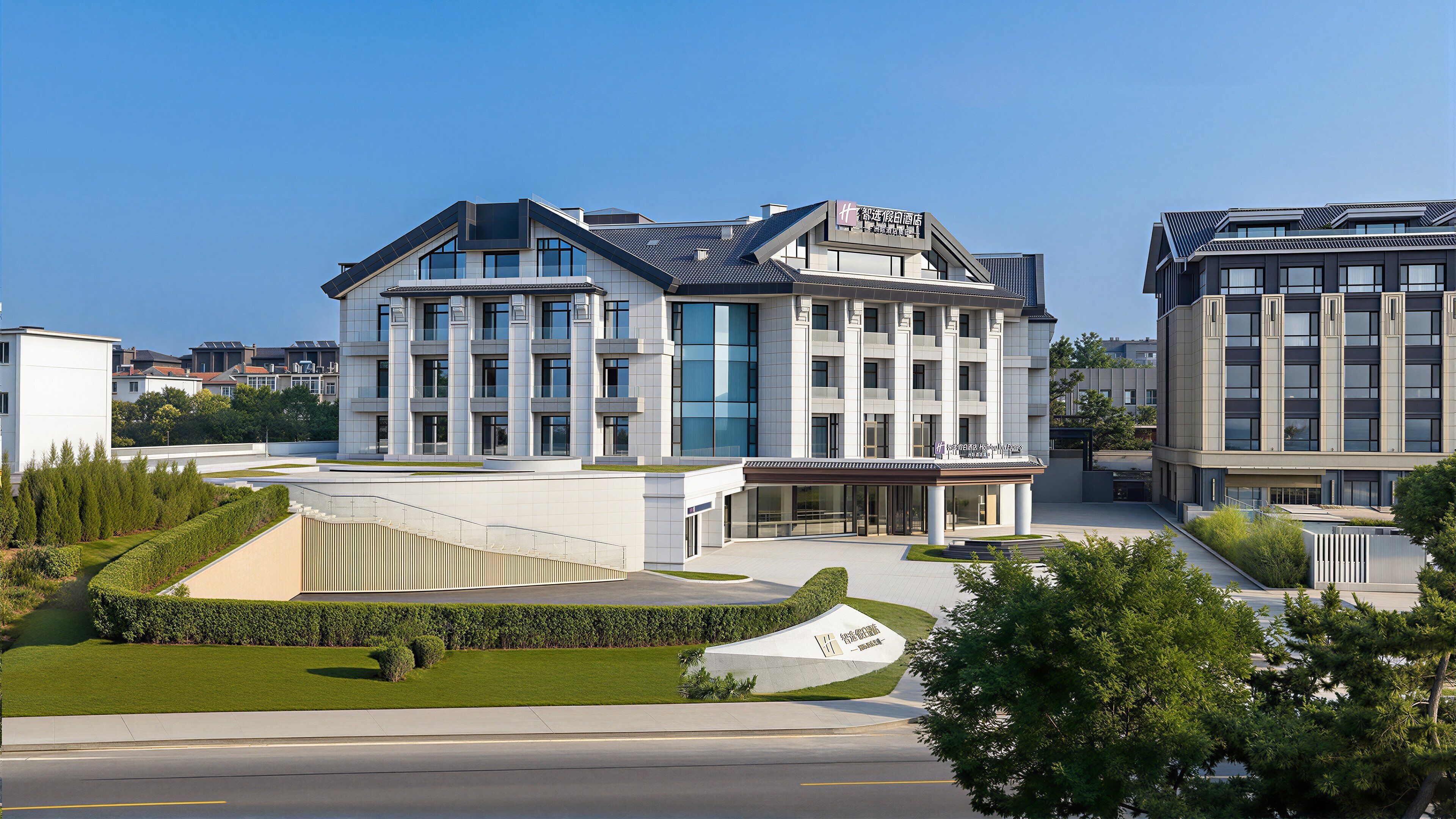 Ein modernes Hotel mit markantem Eingang, einer Dachterrasse und einem angelegten Garten.