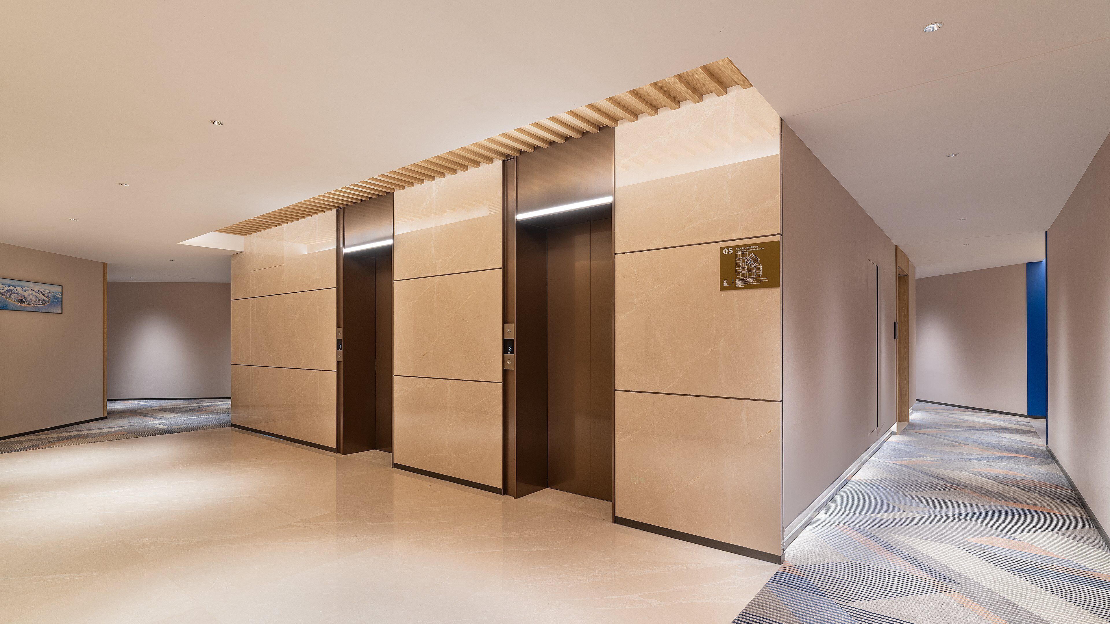 Um corredor com um elevador moderno, piso estampado e parede azul decorativa.