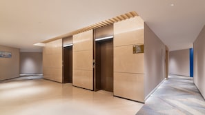 Un couloir doté d’un ascenseur moderne, d’un sol à motifs et d’un mur d’accent bleu.