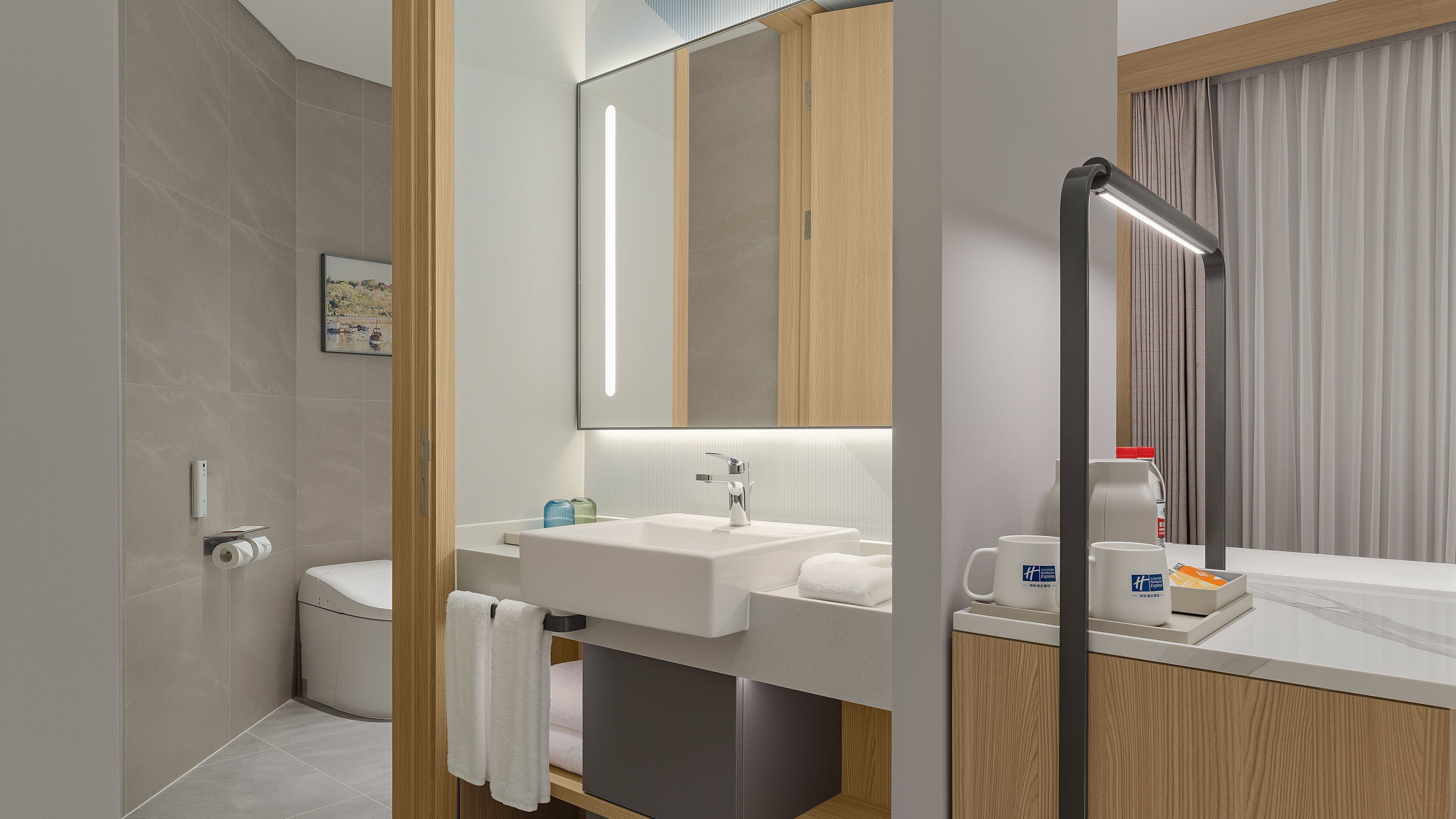 Et moderne badeværelse med bruser, toilet, håndvask og spejl.