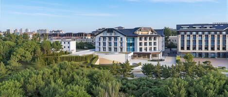 A modern building complex with multiple structures, surrounded by dense greenery.
