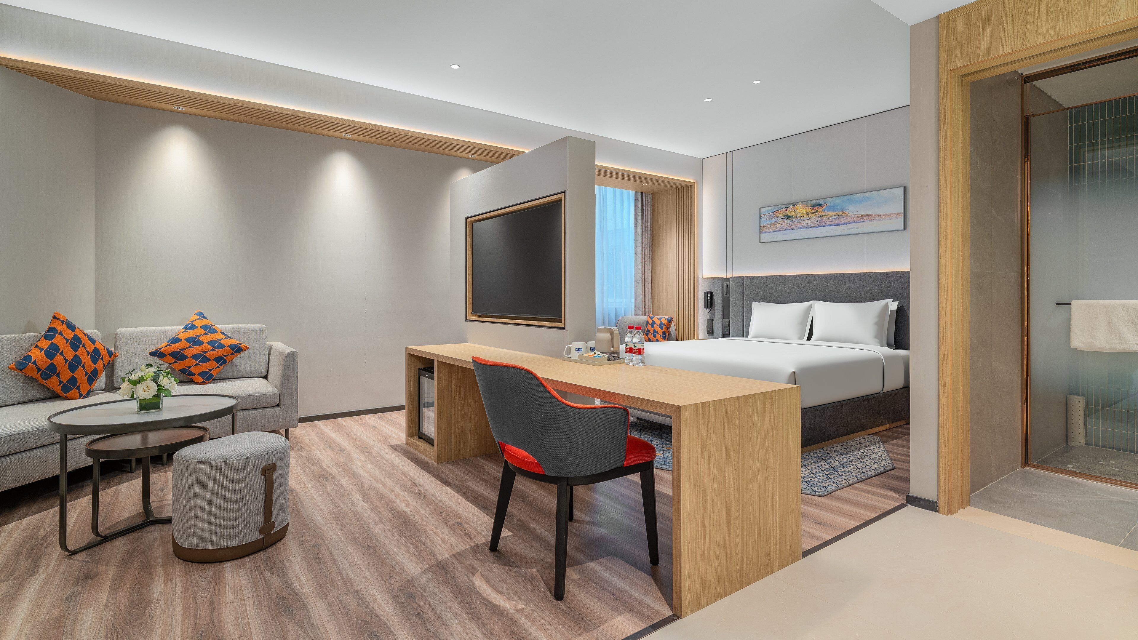 Una habitación de hotel moderna con cama, escritorio, sofá y televisor.