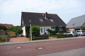 Ein Wohnhaus mit Satteldach, einer Veranda und einem gepflasterten Einfahrt.