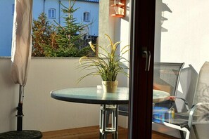 Ein Balkon mit einem kleinen Tisch, einem Blumentopf und einem Stuhl.