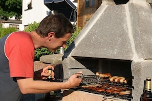 Una persona che cucina all'aperto su una griglia barbecue.