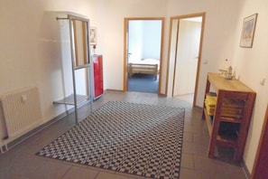 Ein Flur mit einem Schachbrettmuster-Teppich, einem Heizkörper, einem roten Schrank und einer hölzernen Bank.