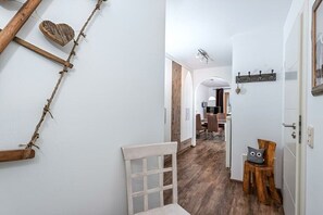 Ein Flur mit einem Holzstuhl, einer herzförmigen Dekoration und einem Kleiderständer.