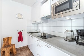 Eine moderne Küche mit weißen Schränken, einer eingebauten Mikrowelle, einem Kochfeld und einer Kaffeemaschine.