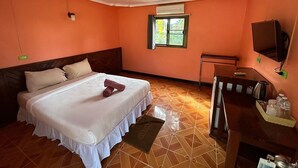 A hotel room with a bed, a desk, a chair, an air conditioning unit, and a television. - Kerdmanee Resort (Ko Chang)