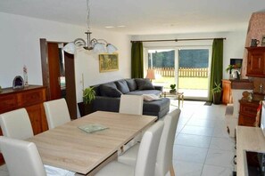 A dining area with a wooden table and chairs, a sofa, and a view of the outdoors through a sliding glass door. - Holiday apartment with 3 bedrooms (Herrischried)