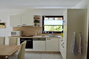 A compact kitchen with white cabinets, a microwave, a dishwasher, and a window with a view of greenery. - Holiday apartment with 3 bedrooms (Herrischried)