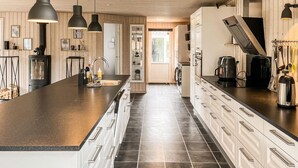 Una cocina moderna con una isla central, electrodomésticos de acero inoxidable e iluminación colgante.