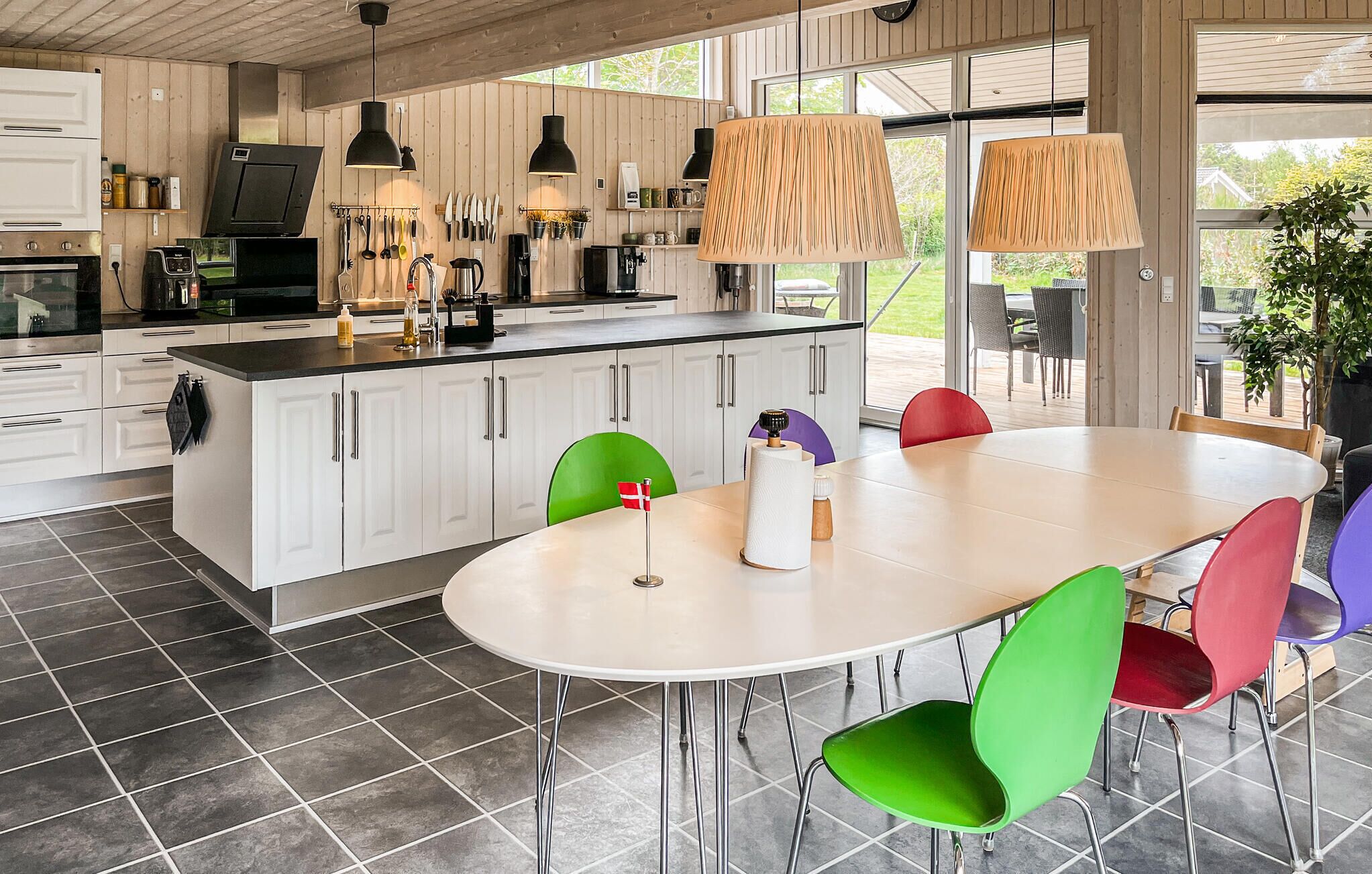 A modern kitchen with white cabinets, a large island, and hanging pendant lights.