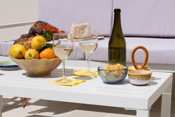 Een tafel met een schaal fruit, wijnglazen, een fles en een decoratieve kom.
