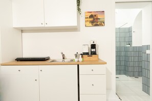 Eine moderne Küche mit weißen Schränken, einer Holz Arbeitsplatte, einem Spülbecken und einer Kaffeemaschine.