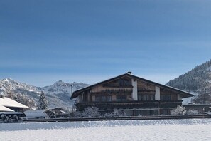 Eine Holzhütte mit Balkon, umgeben von schneebedeckten Bergen.