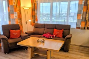 Ein Wohnzimmer mit einer Sofagarnitur, einem Couchtisch und einer Lampe.