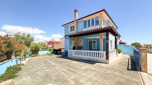 Una casa a due piani con un balcone, un camino in pietra e un vialetto lastricato.