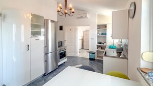 Una cucina moderna con elettrodomestici in acciaio inossidabile, un lampadario e un design lineare.