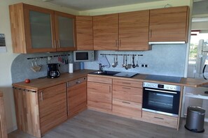 Eine kleine Küche mit Holzschränken, einer Mikrowelle, einer Kaffeemaschine, einem Spülbecken und einem Backofen.