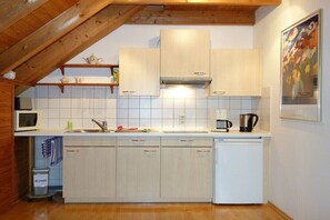 Eine Küche mit Holzschränken, einer Mikrowelle, einer Kaffeemaschine und einem Geschirrspüler.