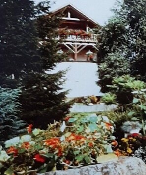 Ein Gebäude mit Balkon, umgeben von üppigem Grün.
