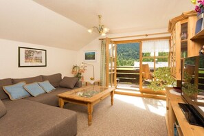 Ein Wohnzimmer mit einer Couch, einem Couchtisch und Blick durch eine Glastür in einen Außenbereich.