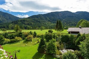 Ein Haus mit Ziegeldach, umgeben von einem üppigen Garten und einer Bergkulisse.