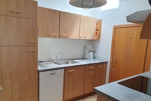 Eine Küche mit Holzschränken, einem Geschirrspüler, einer Spüle und einer Kaffeemaschine.