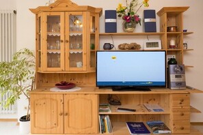 Ein Holz-Multifunktionsmöbel mit einem Flachbildfernseher, Büchern und Dekorationsobjekten.