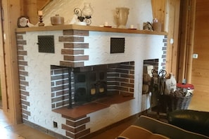 Ein Kamin mit Backsteinmuster, darüber ein Regal und rechts daneben ein Korb mit Gegenständen.